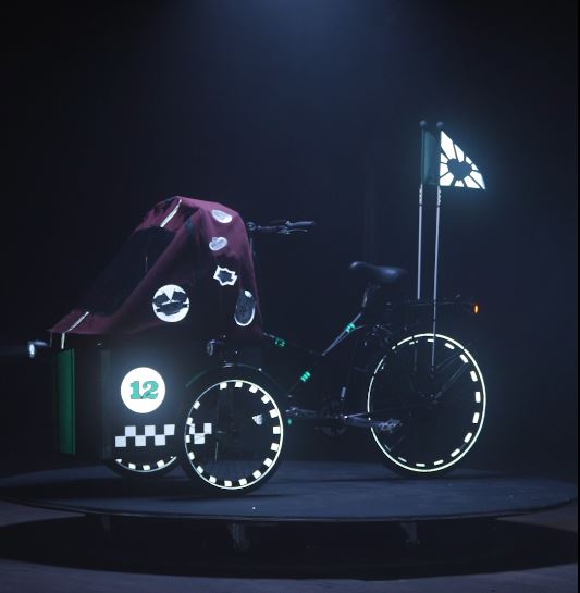 Una bici cargo in stile auto da corsa con bandierina riflettente, adesivi catarifrangenti per i cerchi e divertenti sticker riflettenti