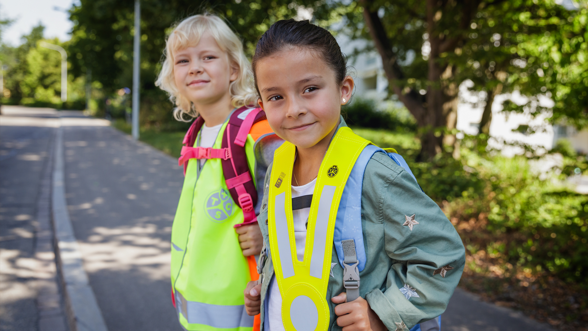 Sécurité sur le chemin de l’école: deux enfants avec gilet réfléchissant et triangle lumineux