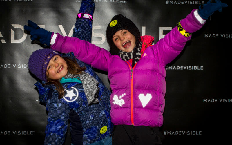 Zwei Mädchen präsentieren sich in ihren mit Reflektorfolien verzierten Jacken